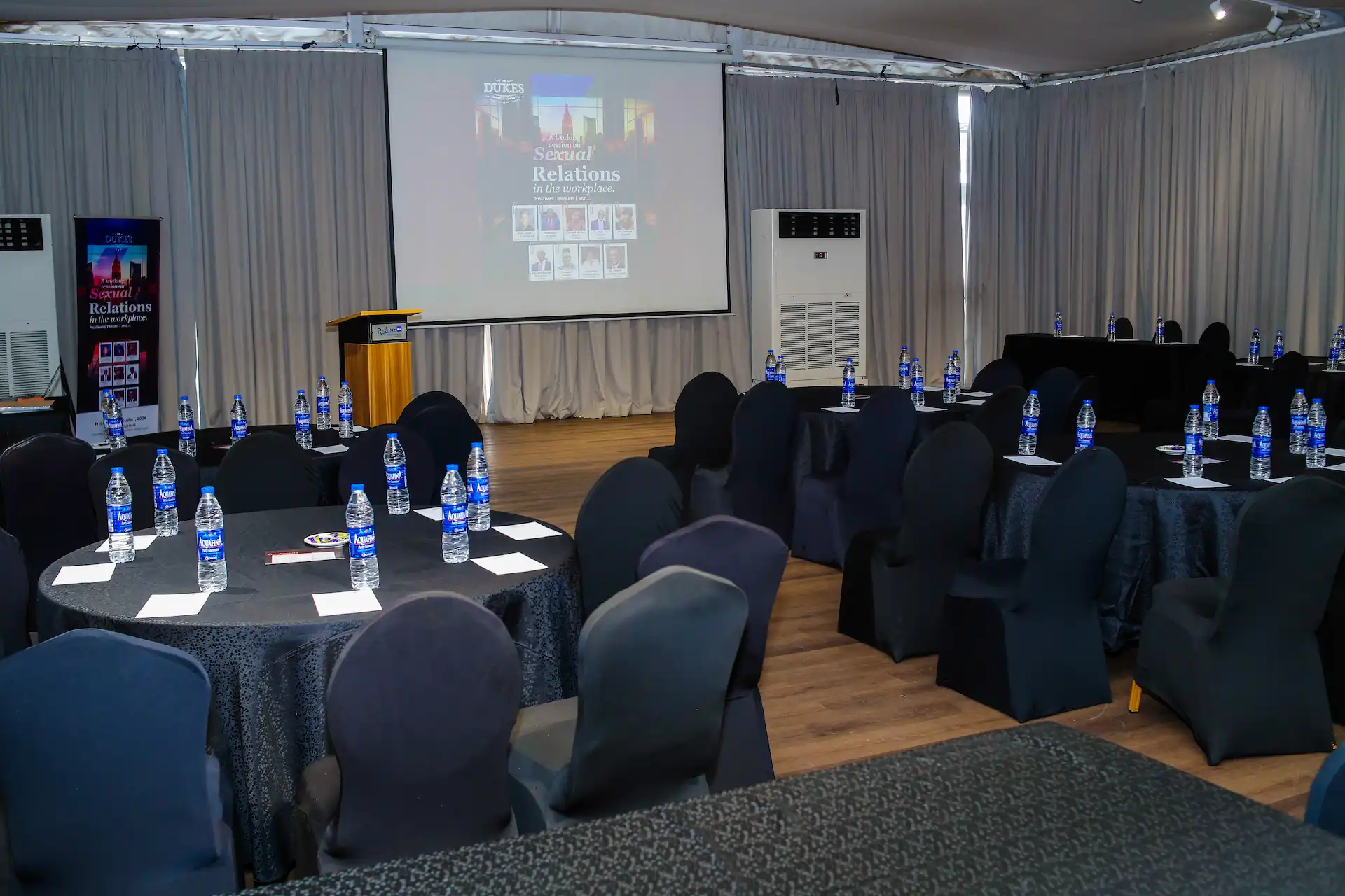 An empty grand hall prepared for a leadership convening, lit by a single shaft of light