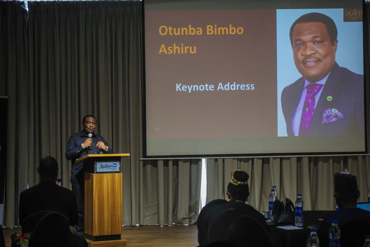 African executive leader in formal dress addressing a hall